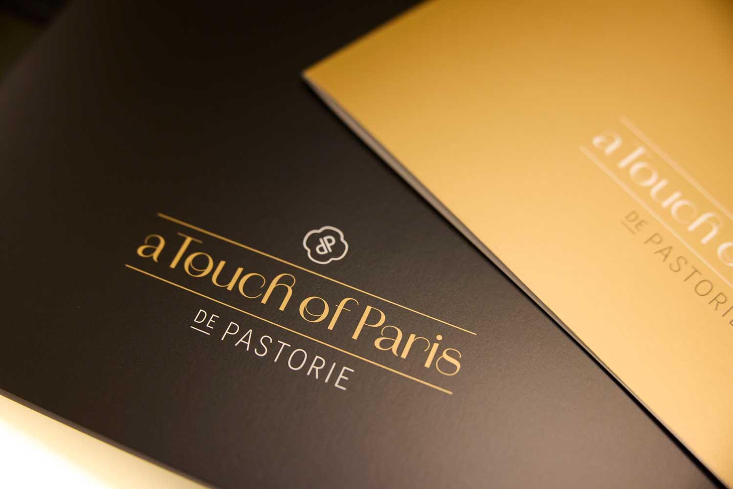 Brandle - Logo luxe drukwerk voor De Pastorie Detailopname van luxe drukwerk voor De Pastorie met goudfolie op een donkere achtergrond.