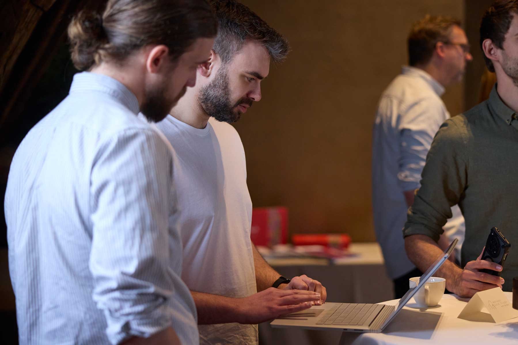 Brandle - netwerkevent S1 Inspires Drie personen bespreken informatie rond een laptop tijdens een professioneel netwerkevent.