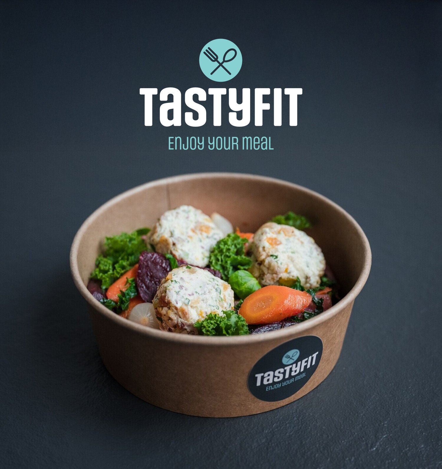 Brandle - Merkcreatie en nieuw logo voor Tastyfit Een take away box gevuld met kleurrijke groenten en drie ronde vegetarische balletjes, geplaatst op een donkere ondergrond. Boven de kom staat het TastyFit-logo met de slogan ‘Enjoy your meal’.